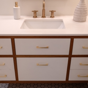 Hall bathroom vanity with white fronts and brass pulls