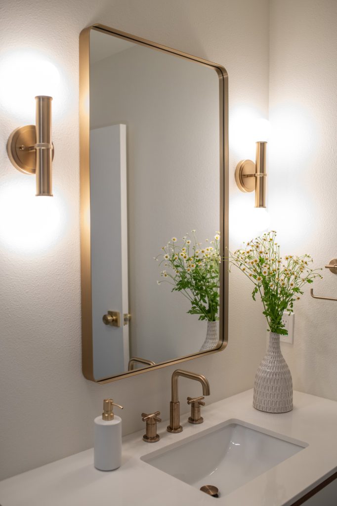 Hall bathroom vanity with brass faucet and mirror