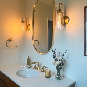 Master bathroom mirror, sconces, and brass faucet