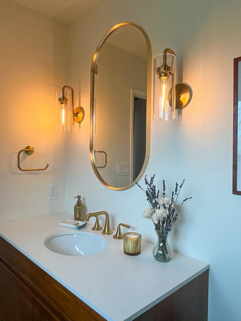 Master bathroom mirror, sconces, and brass faucet