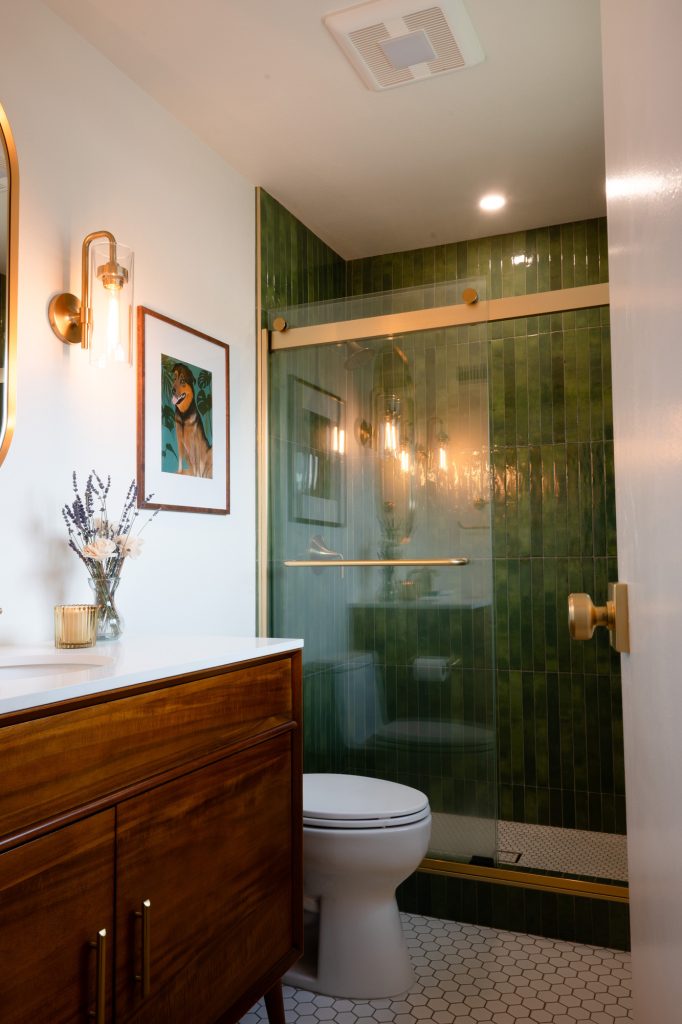 Primary bathroom with walnut vanity and green tiled shower