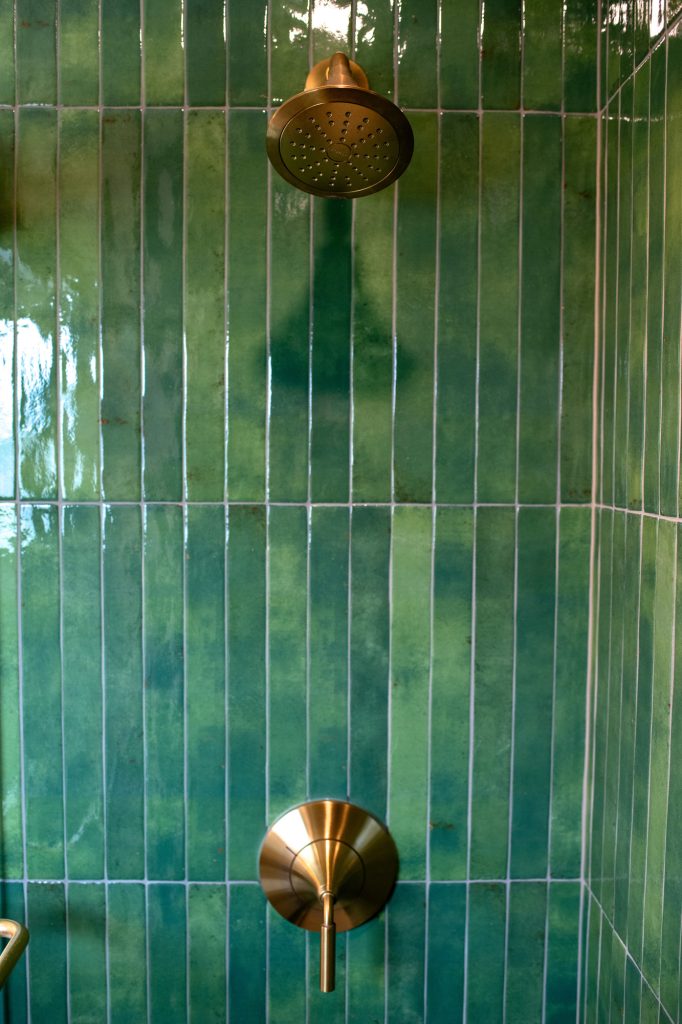 Master bathroom shower head and valve on green tile
