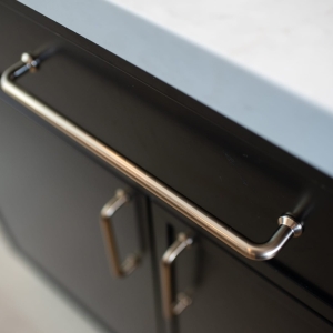 Close-up of a brass bar pull on the black island cabinetry