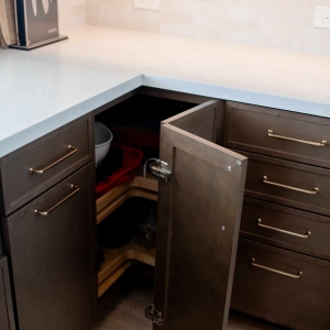 Blind corner cabinet opened to show lazy Susan storage beside the farmhouse sink