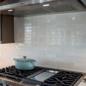 Stainless hood centered over the range with ceramic tile running full height behind it