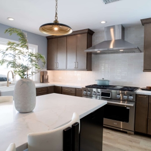 Kitchen island in the foreground with the range and stainless hood along the back wall