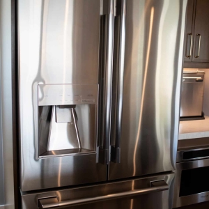 Stainless french door refrigerator beside the built-in microwave drawer and appliance niche