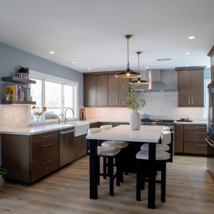 Remodeled kitchen with warm brown shaker cabinetry, a quartz-topped island, and light oak flooring
