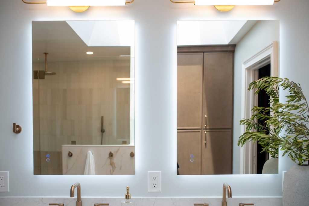 Close view of the two backlit mirrors with their touch controls, shower reflected in one