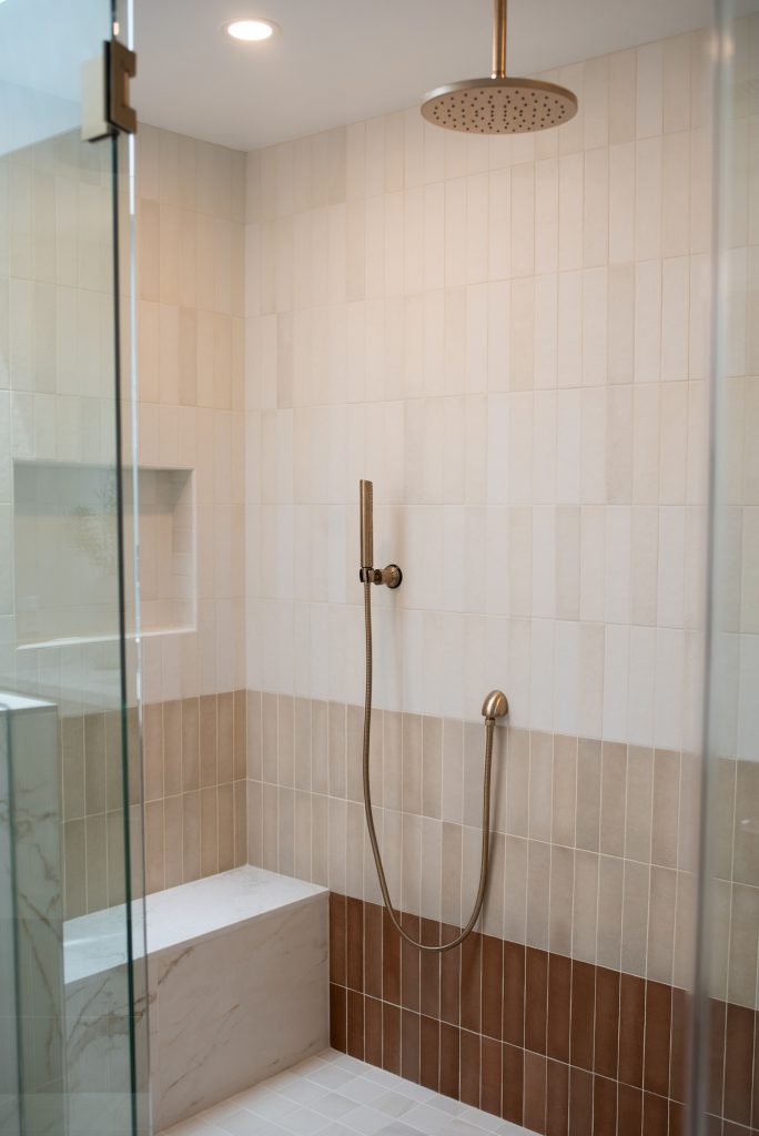Ombre shower wall shading from white through beige to terracotta, with a marble-look bench