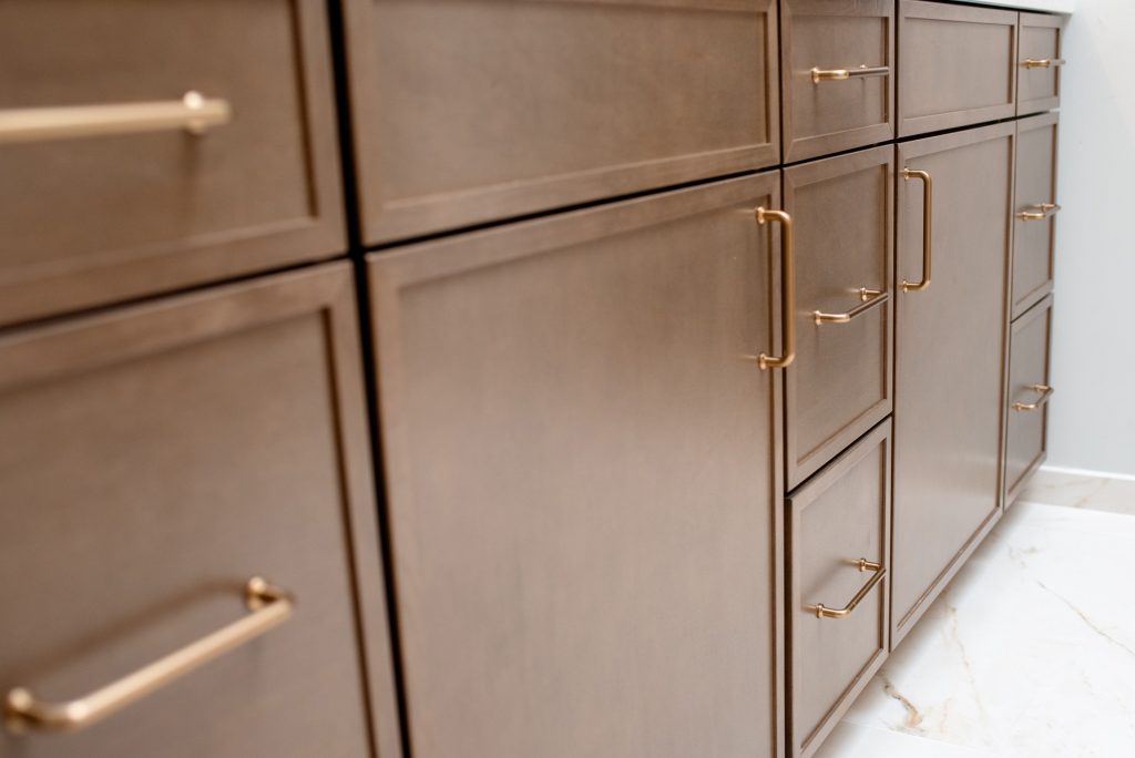 Angled view along the vanity's door and drawer fronts, brass pulls receding toward the wall