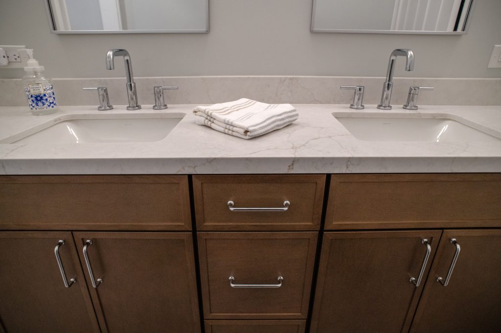 Two chrome faucets and undermount sinks set into the quartz counter, folded towels between