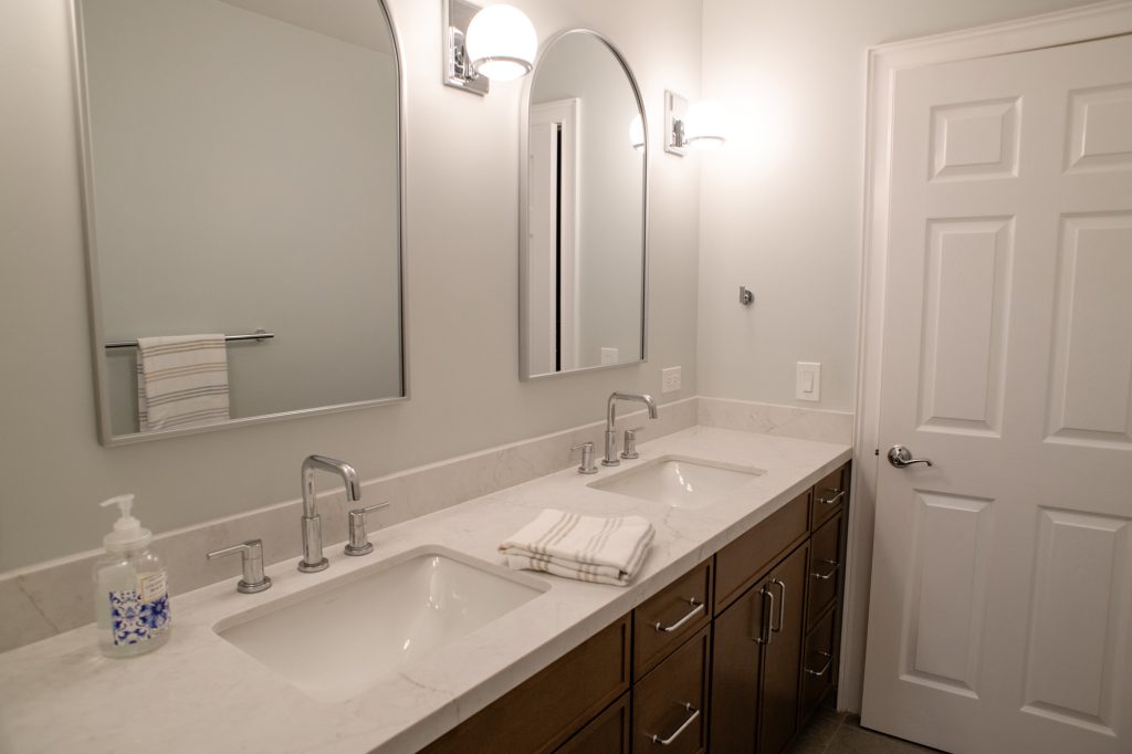 The vanity run from the far end, arched mirrors and globe sconces along the wall