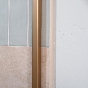 Bronze door channel running down the shower wall beside the tile edge and textured drywall