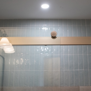 Bronze track and round roller of the Kohler Levity sliding door against glossy blue tile