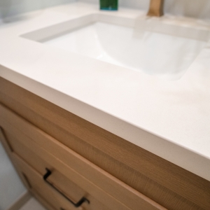 Close view of the white vanity top's square edge over the wood drawer fronts