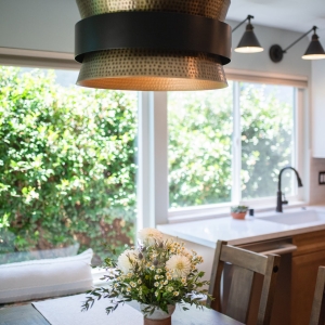 Hammered metal pendant above the table with flowers, sink and window beyond