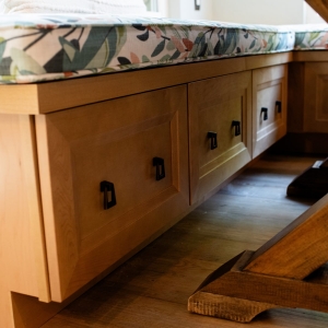 Maple storage fronts beneath the banquette bench with dark drop pulls