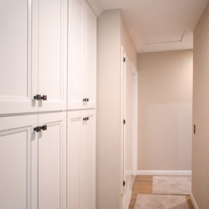 Tall white shaker pantry cabinets with square bronze knobs beside the kitchen
