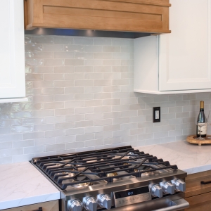 Wood hood surround above the gas range with gloss porcelain tile running behind it
