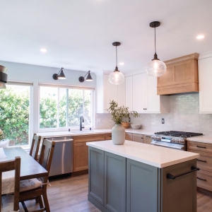 Kitchen with a green island, maple cabinetry, and white uppers beside the banquette table