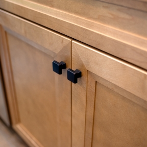 Two bronze knobs on maple shaker doors below a drawer front