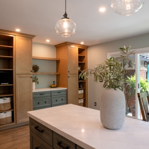 Two tall maple pantries flanking a green buffet with open display shelves between