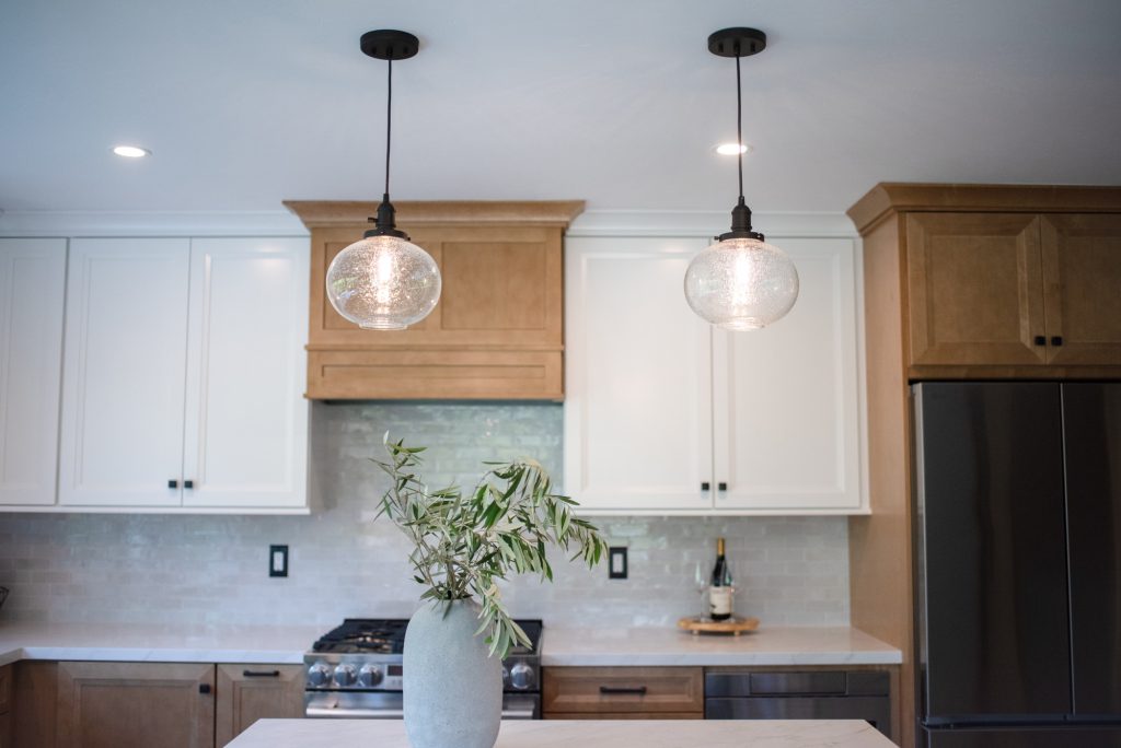 Mini pendant lights hanging over the green kitchen island in a remodeled Mira Mesa kitchen