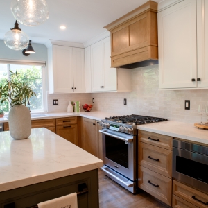 Range wall with the wood hood, gloss backsplash, and microwave drawer beside the refrigerator