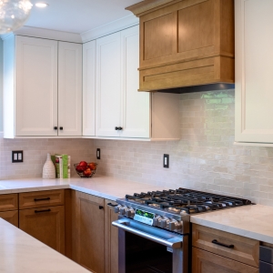 Corner of the kitchen showing white uppers, the wood hood, and the range below