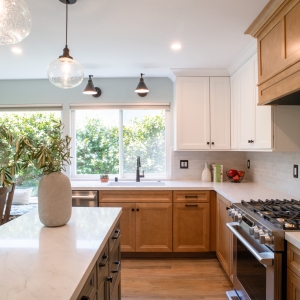 Maple base cabinets along the sink run with the gas range and wood hood on the far wall