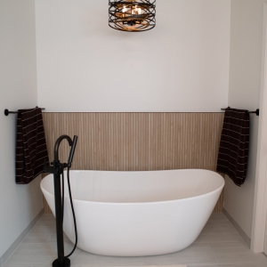 Freestanding soaking tub with a floor-mounted tub filler and towel bars on each side