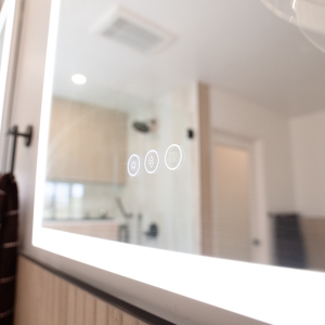 Touch controls glowing on the face of a lighted mirror