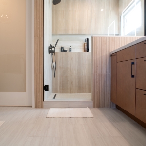 Shower entrance beside a frosted glass door to the water closet
