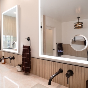 Lighted mirror reflecting the tub and chandelier across the room
