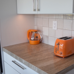 Orange kettle and toaster on a porcelain counter beside the wall oven