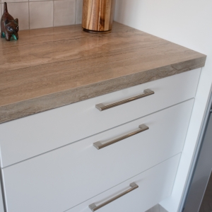 Corner of the porcelain countertop over white drawers next to the refrigerator