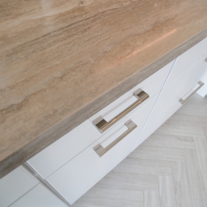 Overhead view of the countertop edge and stainless pulls above the herringbone floor