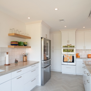 Full kitchen with floating shelves, refrigerator, wall ovens, and a flush ceiling hood above the island
