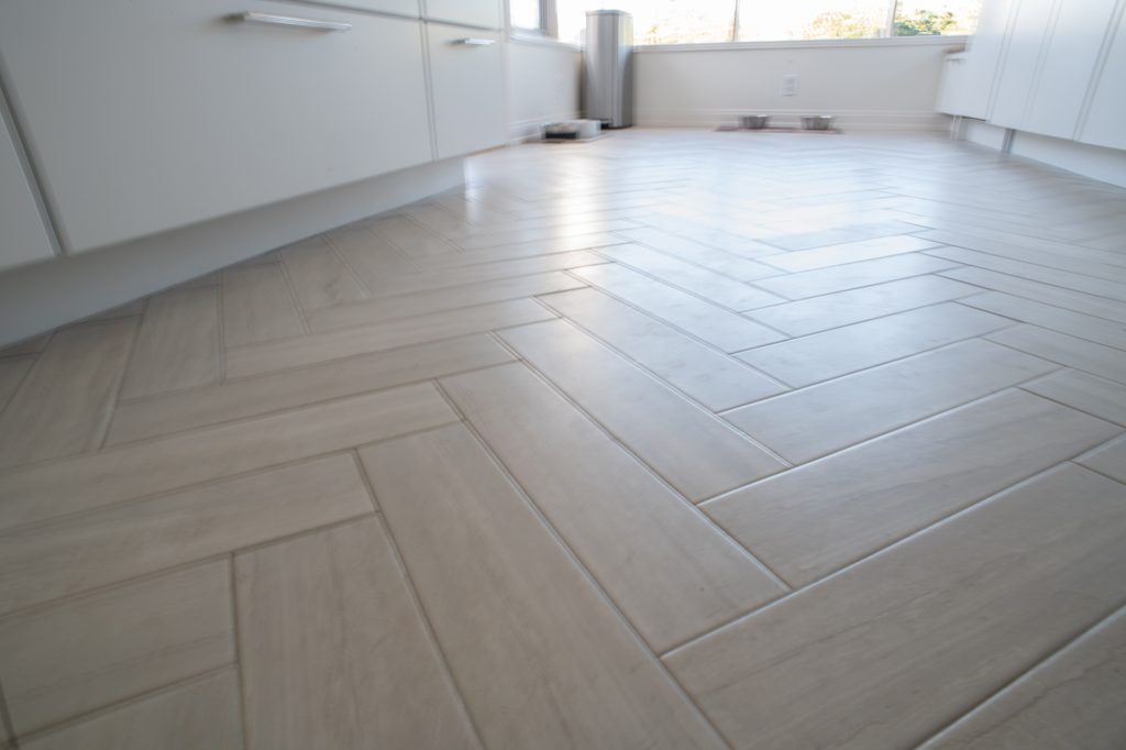 Limestone-look porcelain tile in a herringbone pattern on a remodeled Point Loma kitchen floor
