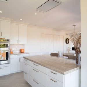 Island with drawer storage below a ceiling-mounted range hood, dining room beyond