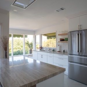 Porcelain-topped island in front of white cabinetry, a French door refrigerator, and a wall of windows