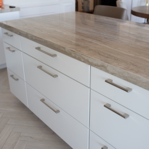 Stacked island drawers with long pulls under a thick veined porcelain edge