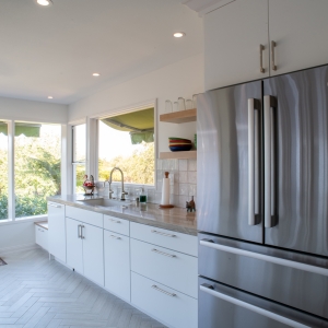 White flat-panel base cabinets leading to a low storage bench under the corner windows