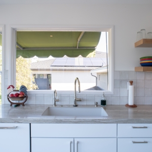 Undermount sink with pull-down and beverage faucets beneath a window, square glazed tile around it