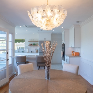 Dining table under a glass chandelier, opening straight into the kitchen