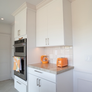 Wall oven and microwave combination beside a short counter with tile backsplash