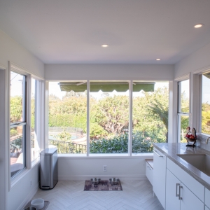 Corner of tall windows overlooking the yard and pool, with the sink run on the right